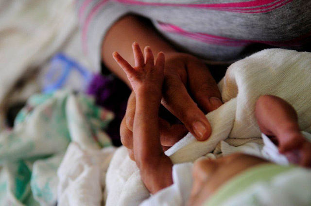 image of newborn child's hand touching mother's finger