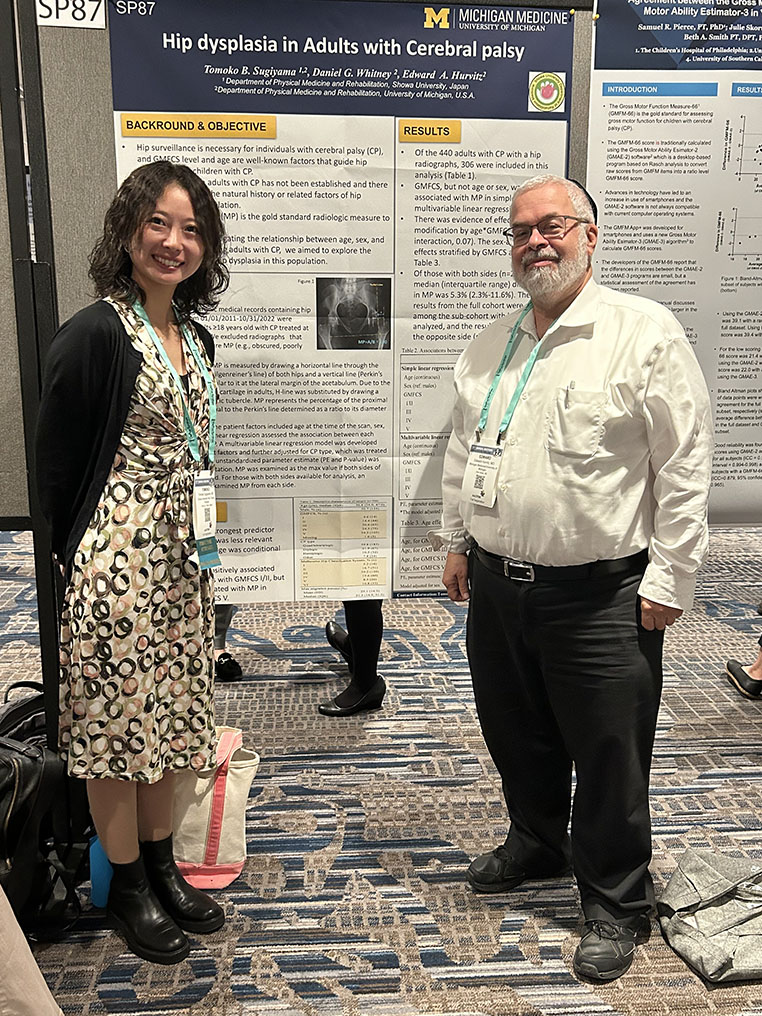 Dr. Ed Hurvitz stands with a co-investigator in front of their research poster titled "Hip dysplasia in Adults with Cerebral Palsy"