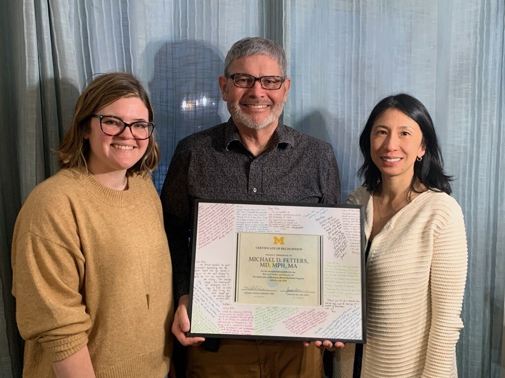 Photo of Assistant Professor Melissa DeJonckheere, Professor Mike Fetters and Assistant Professor Justine Wu. Dr. Fetters is holding a framed certificate of recognition. Photo by Satoko Motohara.