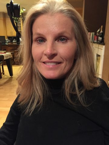 Photo of Vanessa Lavin, a woman with a Spinal Cord Injury. The photo features her from the waist up and she is wearing a dark turtleneck shirt. She has shoulder length blonde hair and is smiling towards the camera.