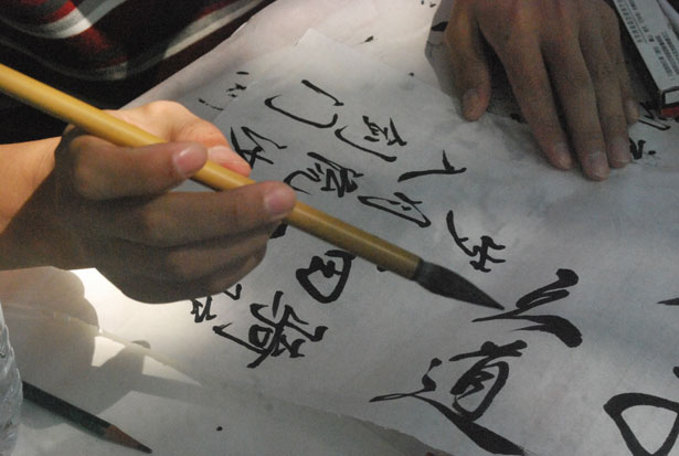 image of hand holding paintbrush to write chinese calligraphy