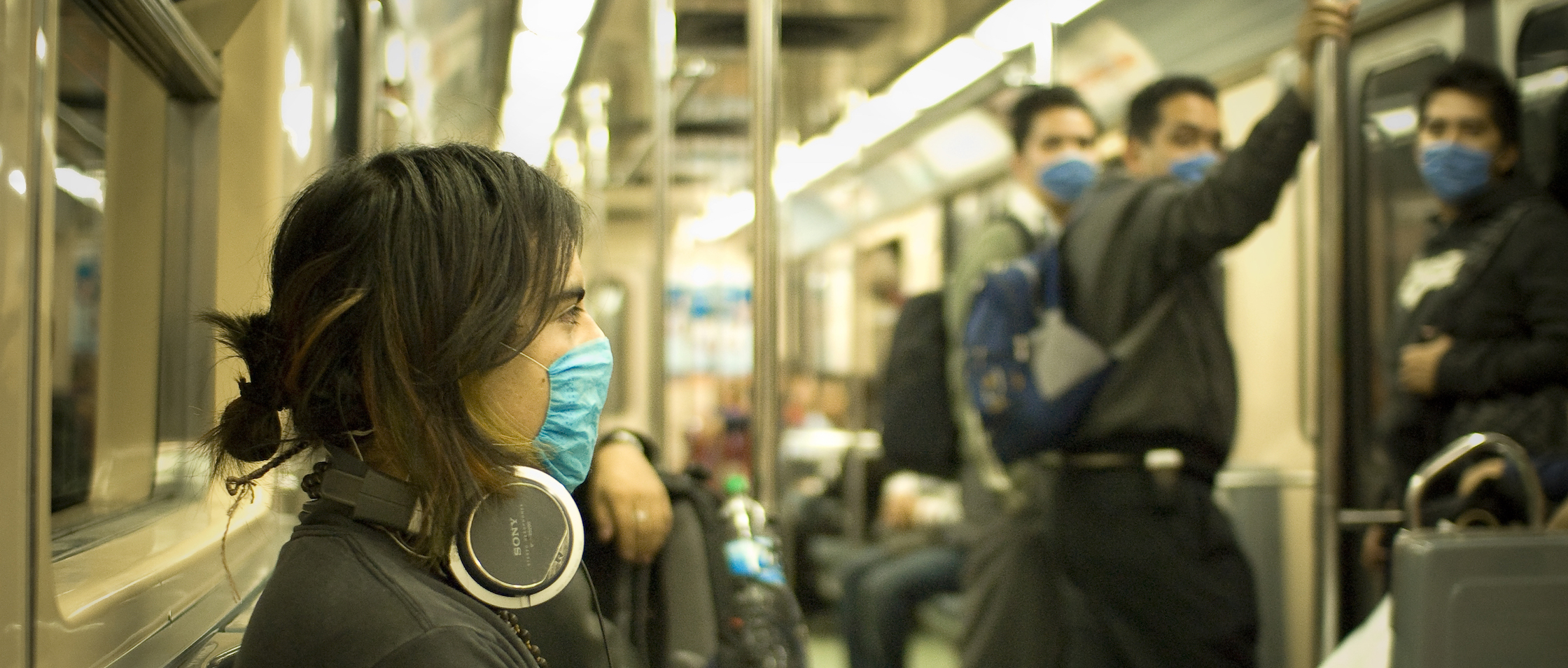 Women and men wearing face masks while riding public transportation