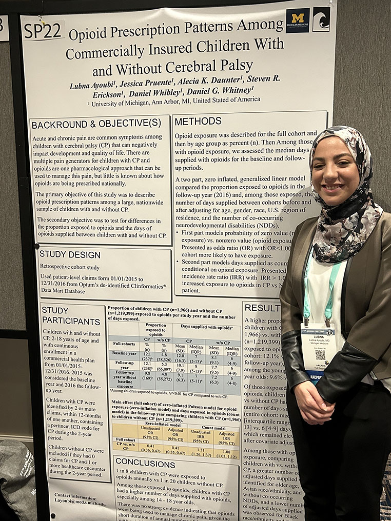 Dr. Lubna Ayoubi stands in front of her research poster titled "Opioid Prescription Patterns Among Commercially Insured Children With and Without Cerebral Palsy"