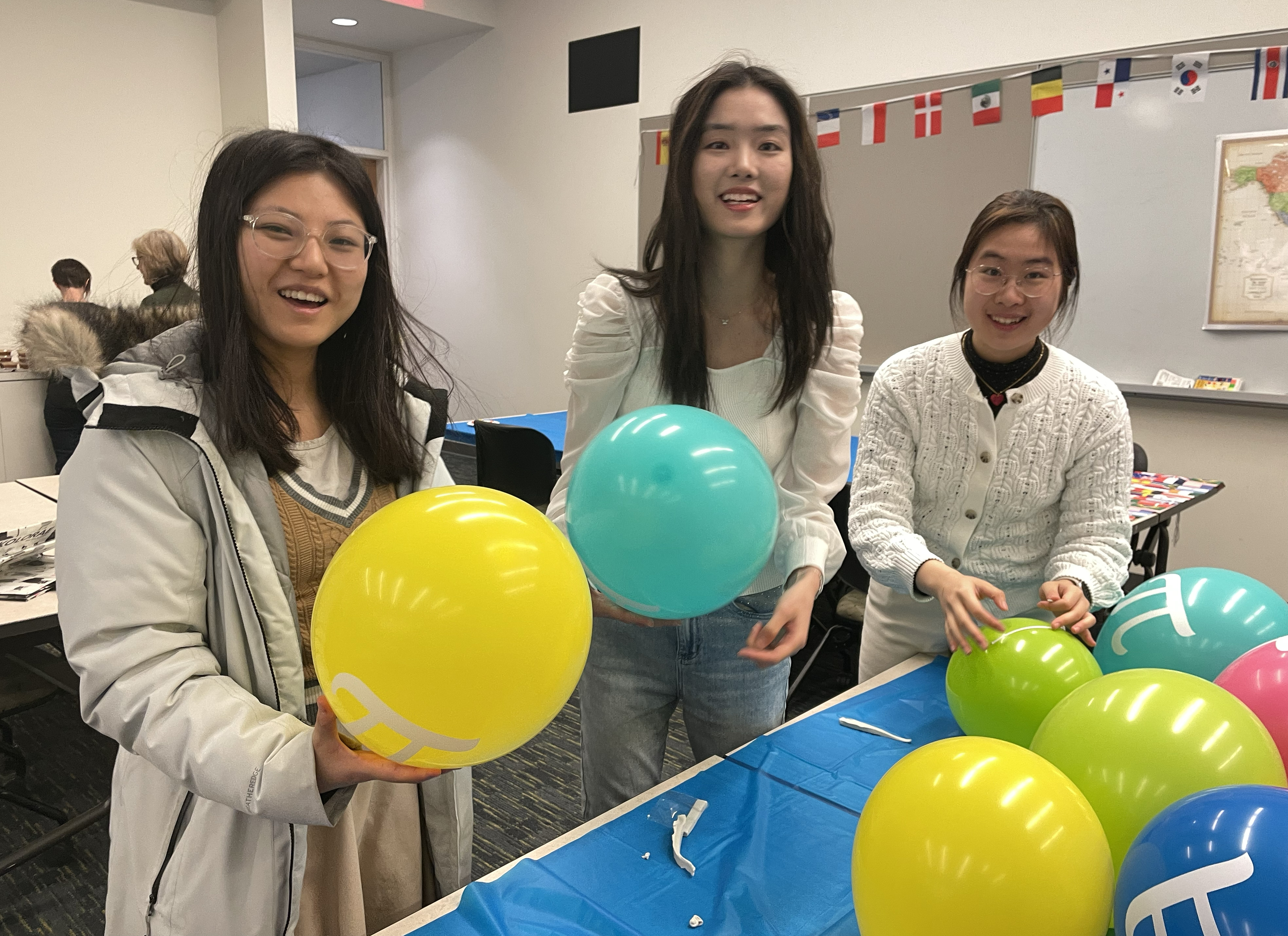 Asian girls help install balloons with pi symbol