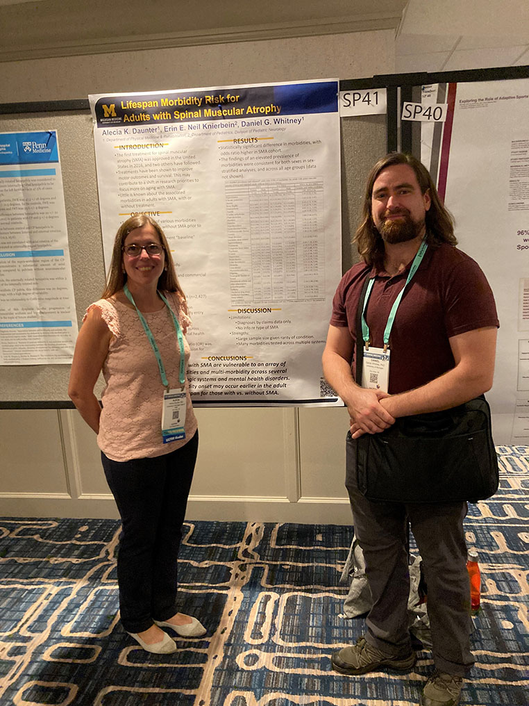 Drs. Alecia Daunter and Daniel Whitney stand in front of their research poster titled "Lifespan Morbidity Risk for Adults with Spinal Muscular Atrophy" 