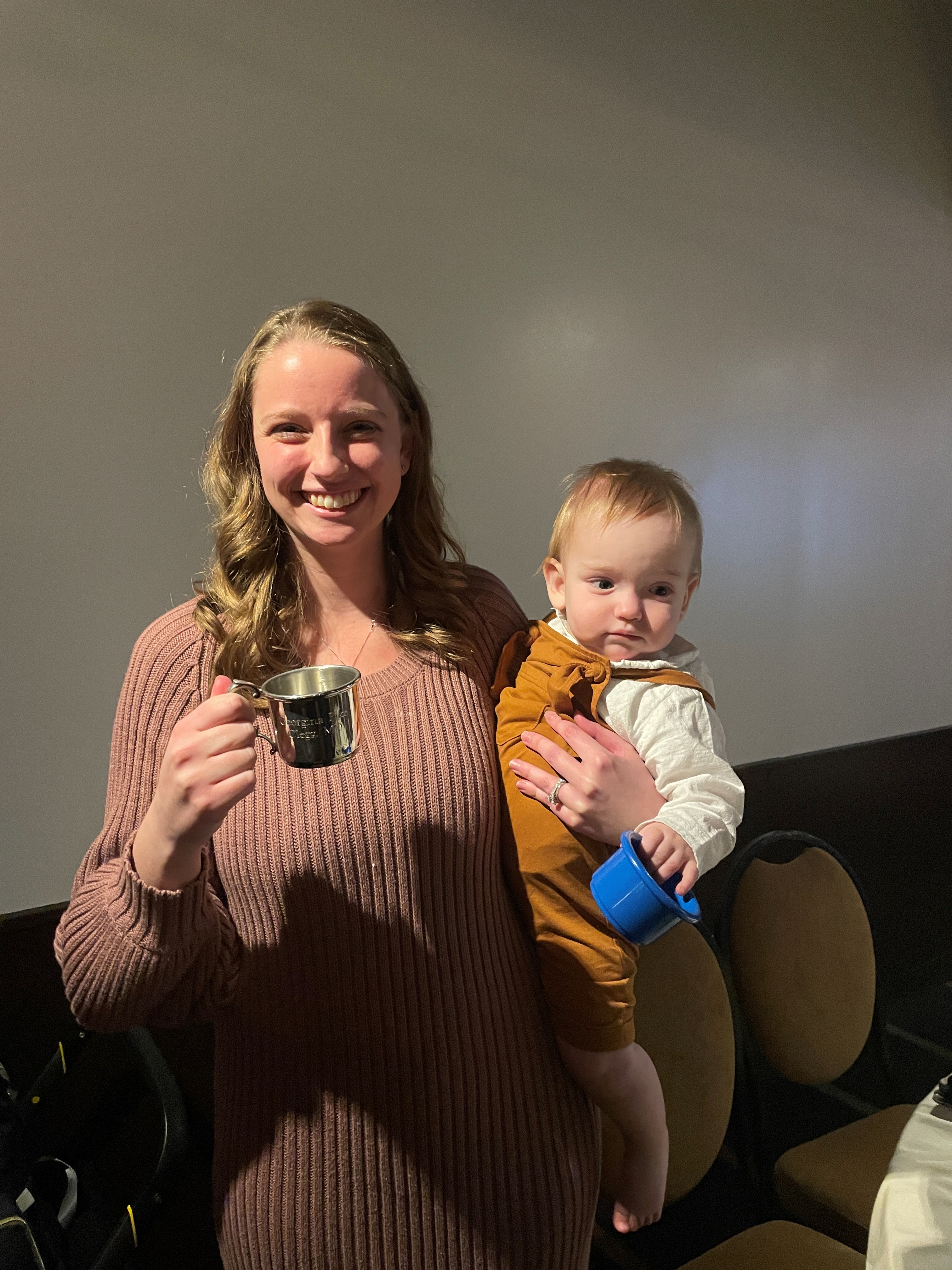 Woman holding a coffee mug and a baby. 