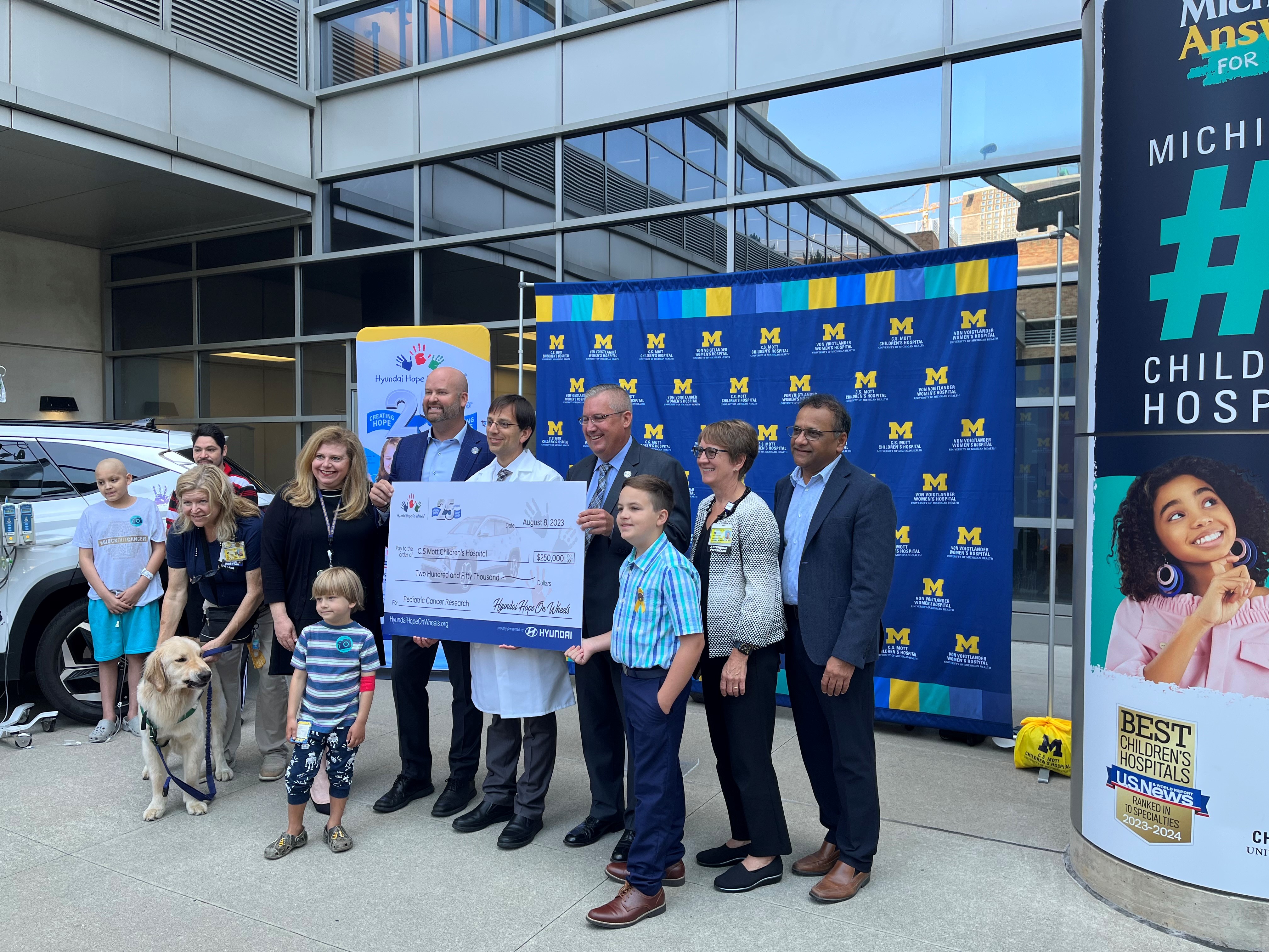 Hyundai holding a $250k check with other hospital leadership to support pediatric cancer.