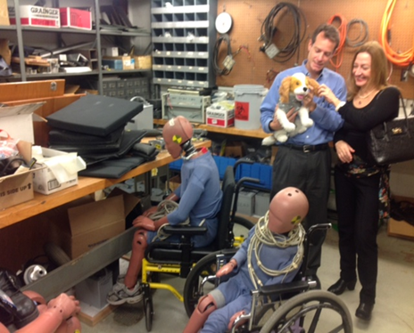 Staff from the U-M transportation lab stand next to crash dummies sitting in manual wheelchairs.in 