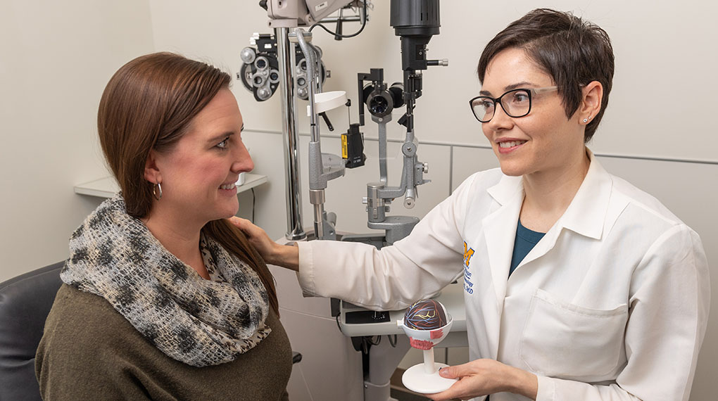Dr. Lindsay De Lott explains to a female patient how optic neuritis affects the eye.