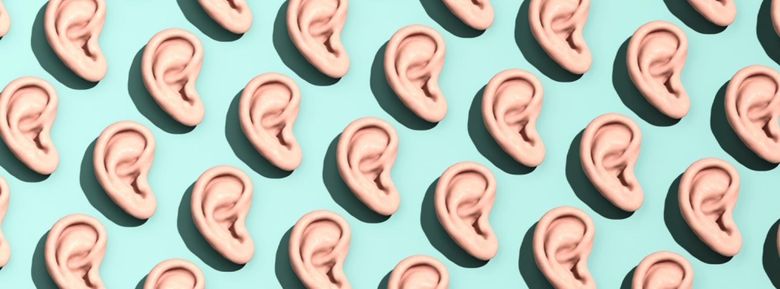 3D photo realistic rendering of human ears arranged in a diagonal pattern on a light green background