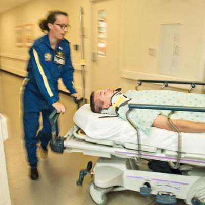Emergency Medicine residents wheel gurney down hall