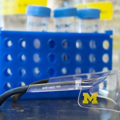 Pair of lab glasses with University of Michigan logo and lab equipment on counter
