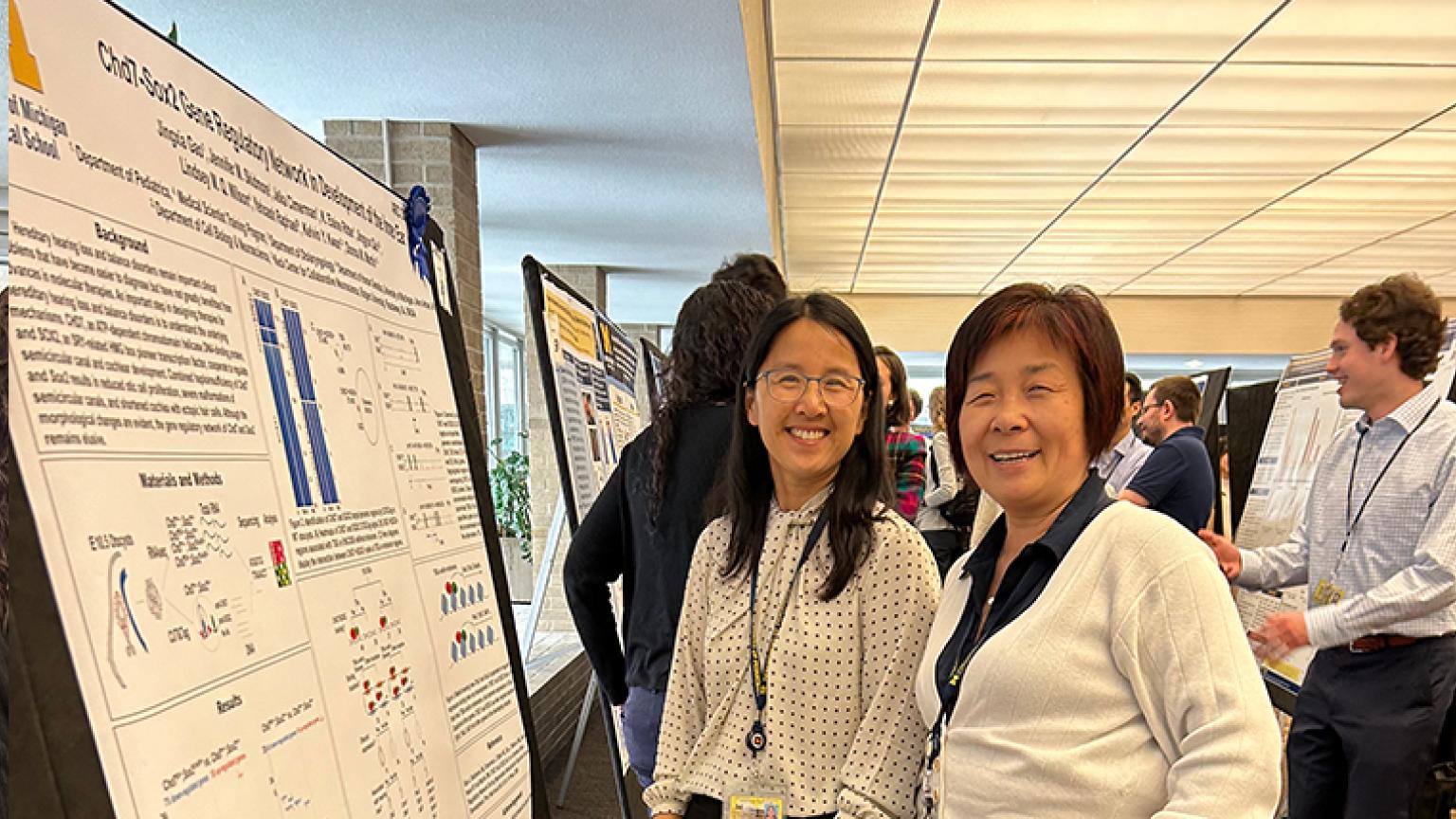 Researchers smiling and posing with presentation posters.