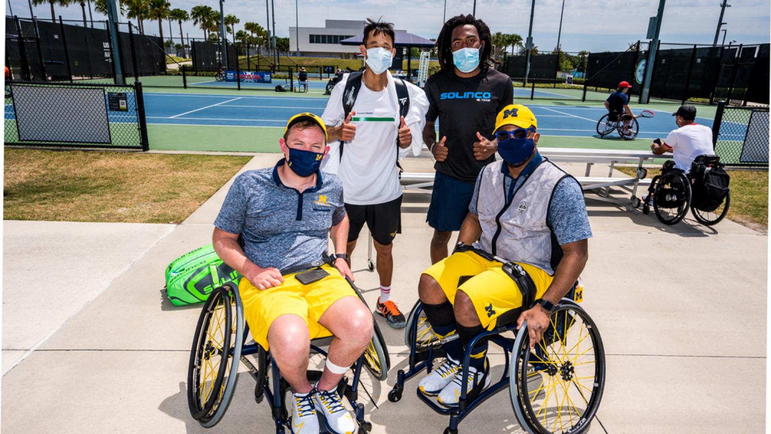 Two University of Michigan tennis players posing with two professional tennis players. 