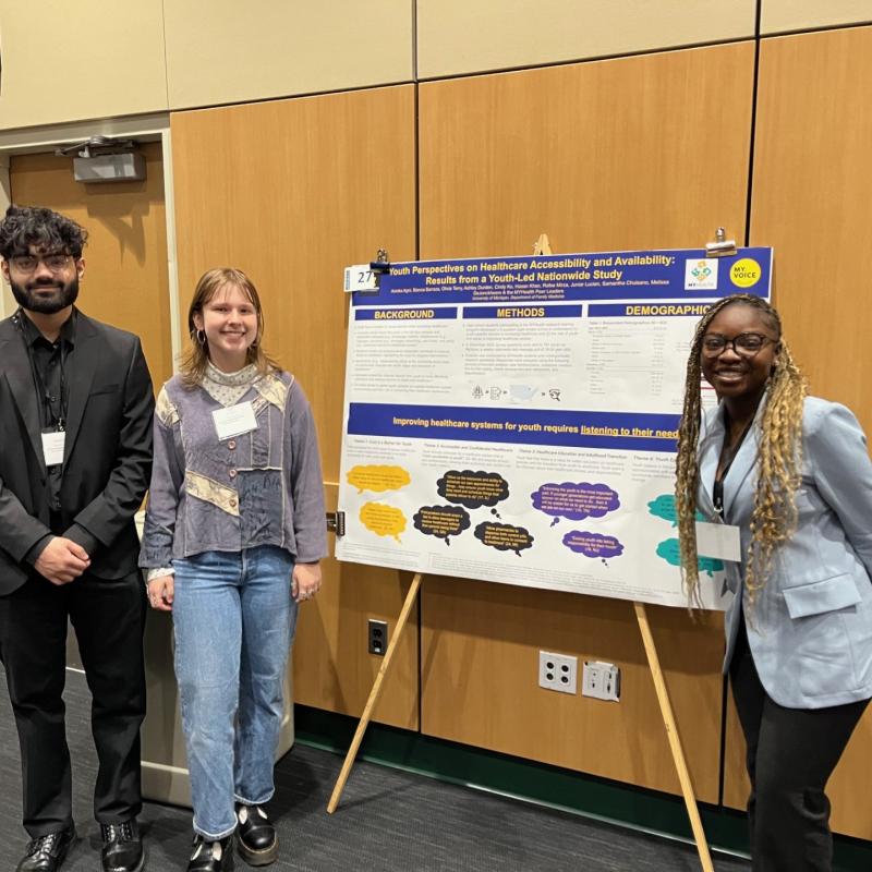 Research Associates Hasan Khan, Liv Terry and Mornikeji Ojubanire posing in front of a large research poster