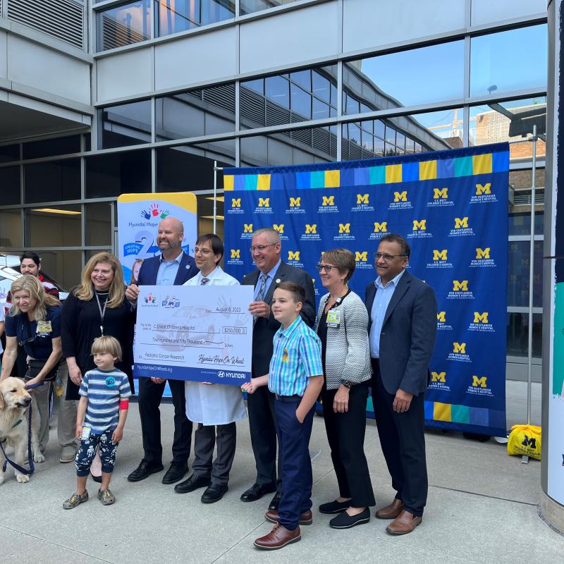 Hyundai holding a $250k check with other hospital leadership to support pediatric cancer.