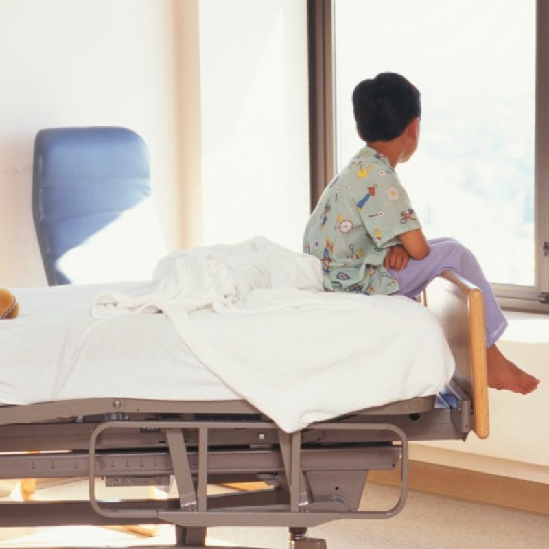 child sitting in hospital bed with window