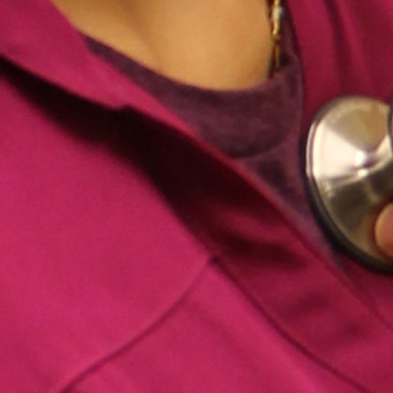 Close up image of a physician holding a stethoscope to a patient's chest
