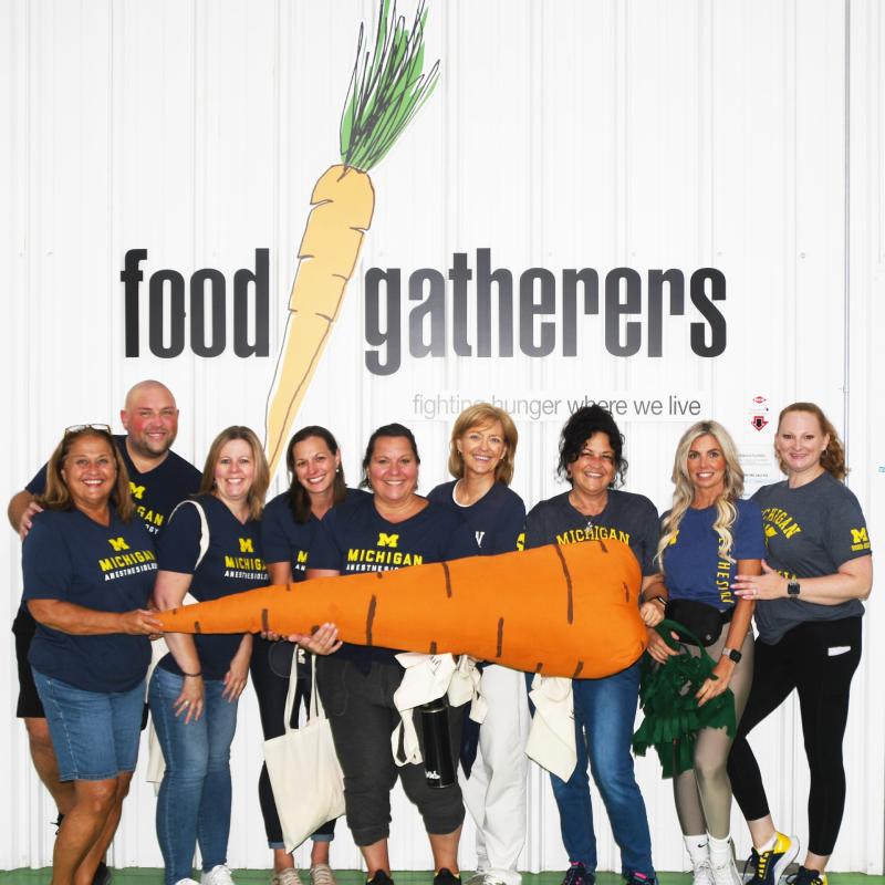 Department volunteers pose in front of Food Gatherers sign
